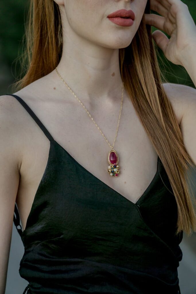 A woman wearing a stylish necklace with a vibrant gemstone pendant, showcasing fashion elegance.