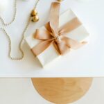Top view of a beautifully wrapped gift with gold decorations on white surface.